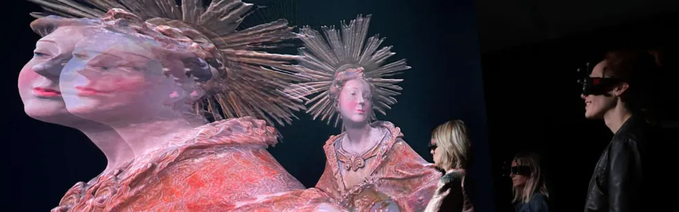 People view a digital 3D hologram of an angelic figure with a radiant headdress.
