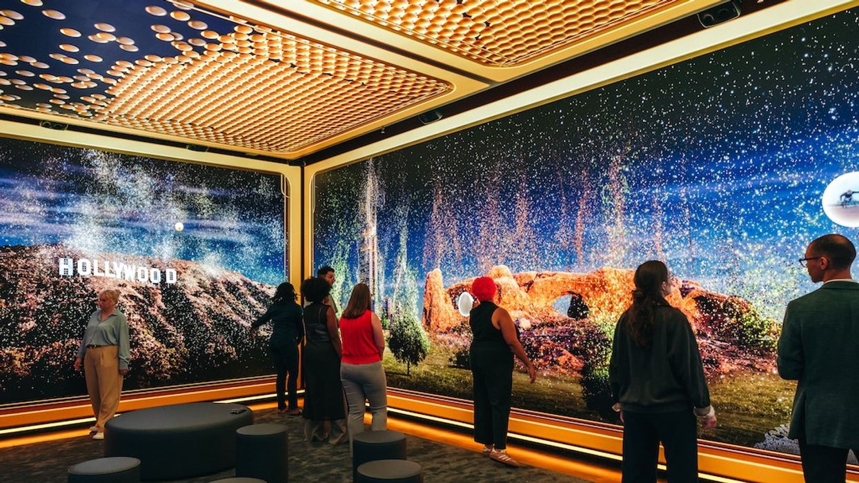 People viewing a digital display with the Hollywood sign and landscapes in a modern exhibit room.