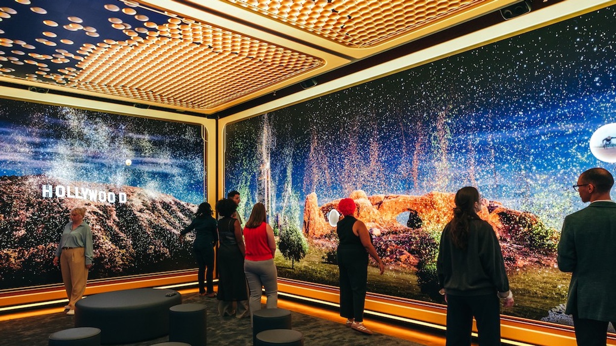 People viewing a digital display with the Hollywood sign and landscapes in a modern exhibit room.