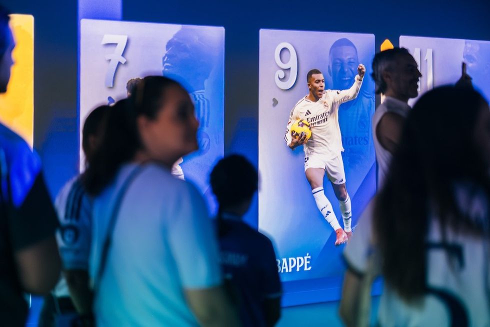 People viewing a football player poster display in a dimly lit room.