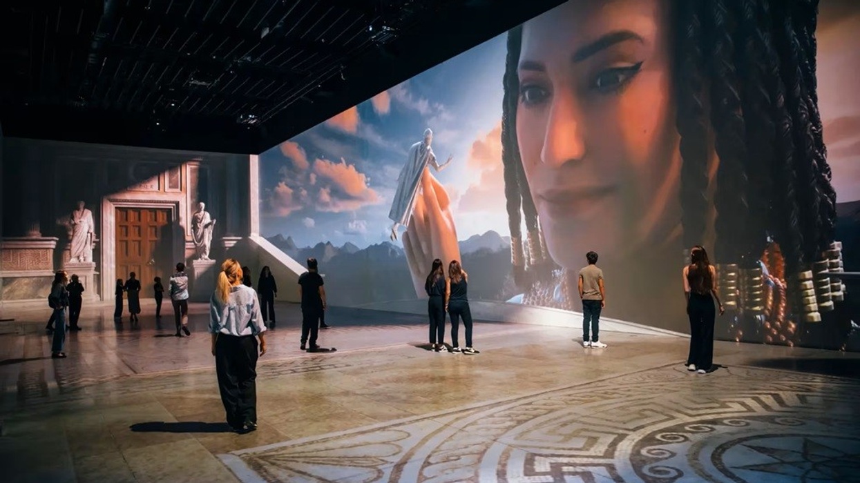People viewing a large digital art installation with classical and modern elements.
