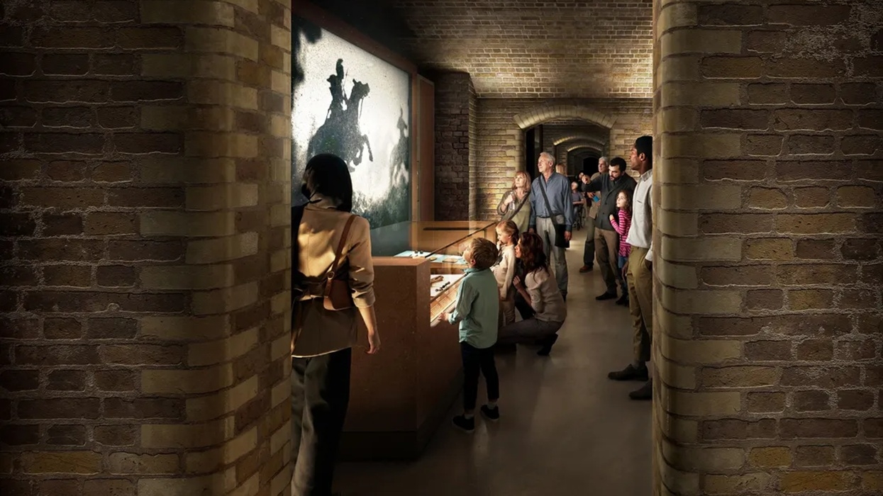 People viewing museum exhibits in a brick-walled corridor at London Museum