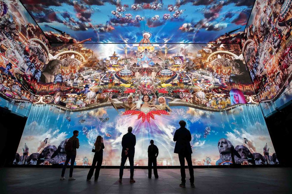 People viewing vibrant, immersive digital art on large, surrounding screens.