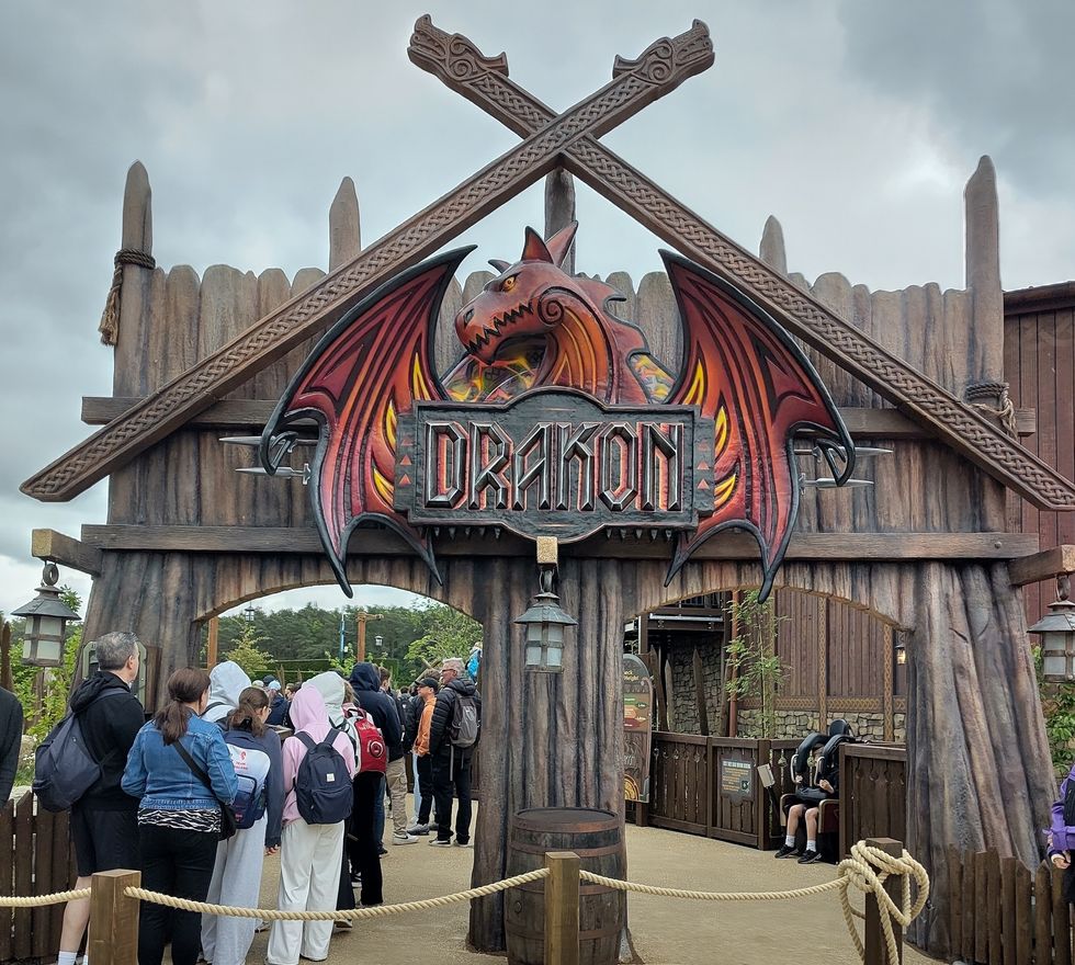 People waiting at the entrance of a ride with a dragon-themed sign reading "Drakon."