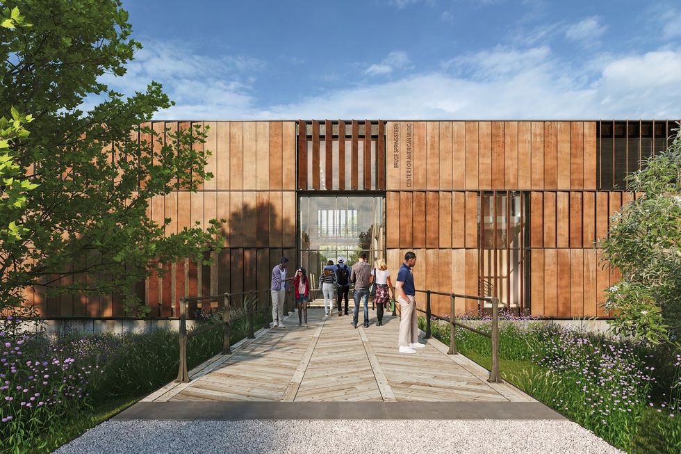 People walking towards the wooden building entrance of the Bruce Springsteen Center for American Music with a landscaped path.