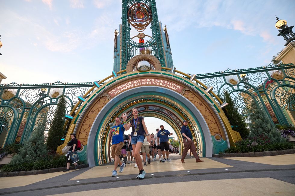 People walking under a colorful, ornate archway at Universal Epic Universe with an inspirational message.