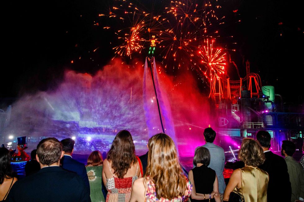 People watch a colorful nighttime fountain and fireworks show.