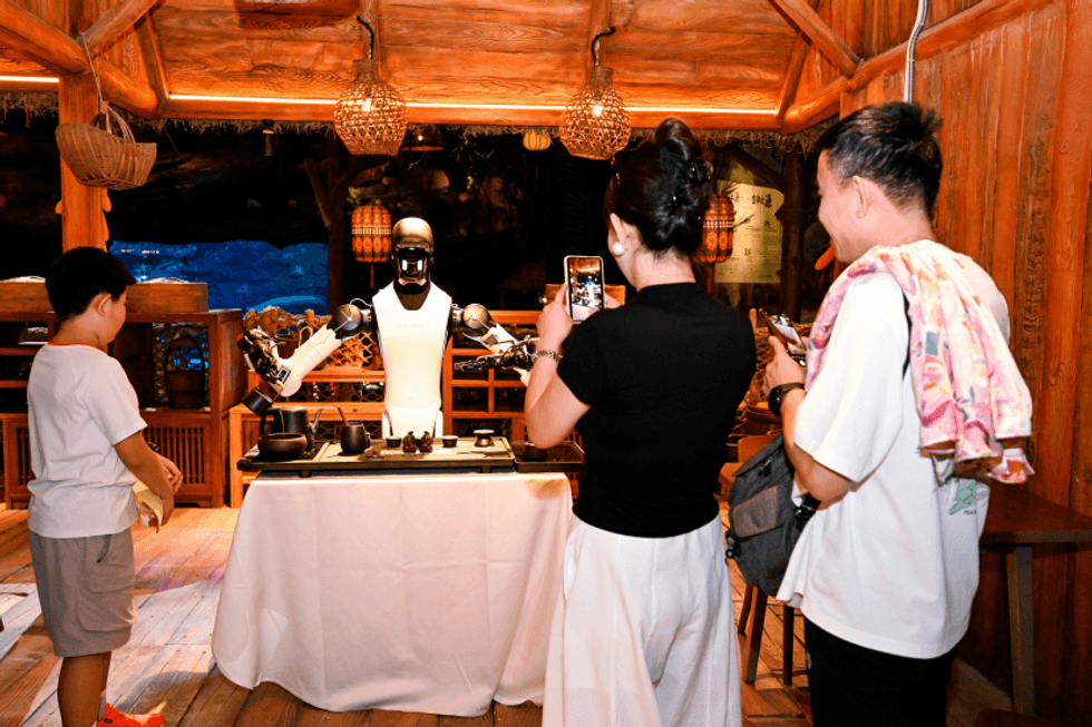 People watching a robot demo at a tea shop, taking photos with their phones at Chimelong Spaceship
