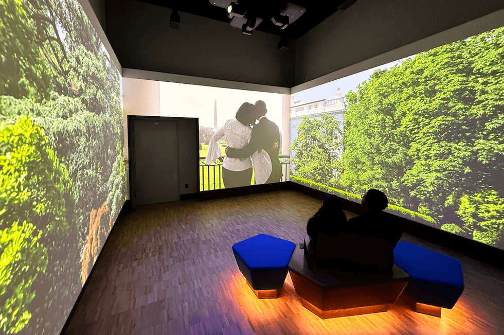 People watching nature projections on walls in a dark room.