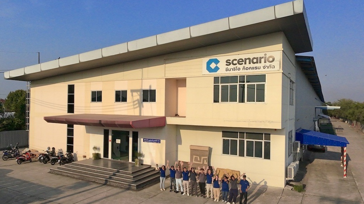 People waving in front of a beige industrial building with a "scenario" sign.
