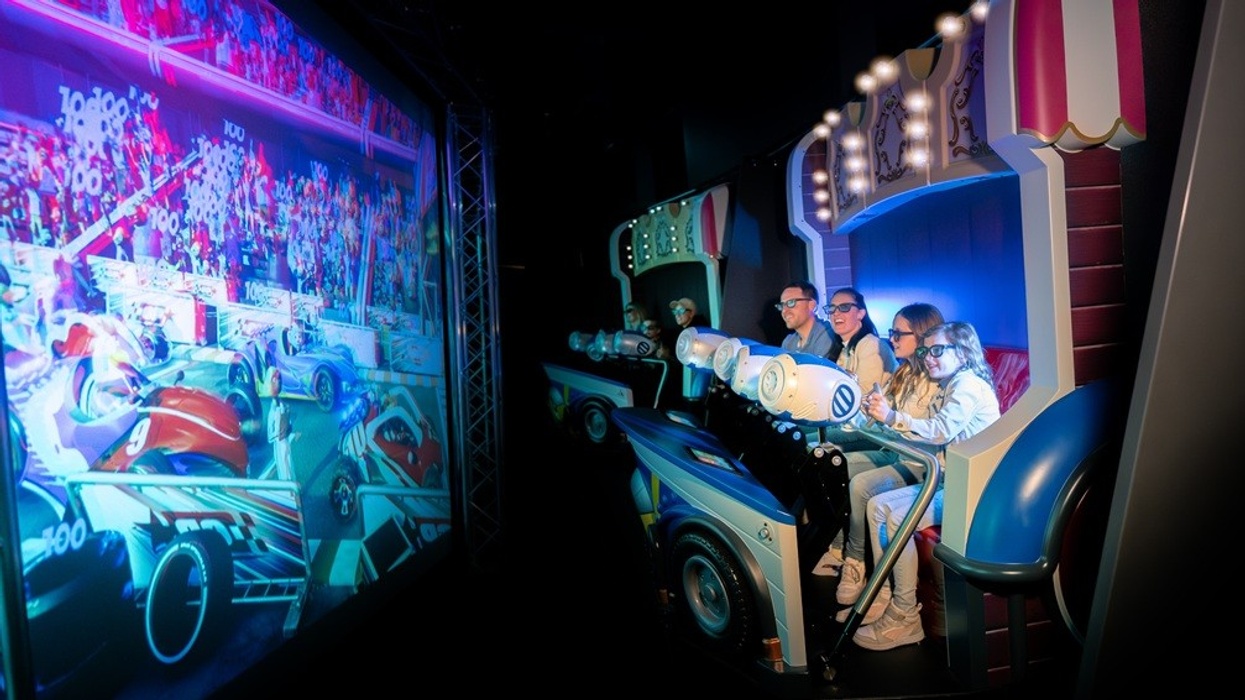 People wearing 3D glasses enjoy an interactive racing game at an amusement attraction.