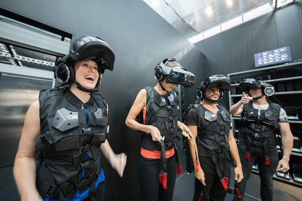 People wearing VR headsets and vests inside a tech room.