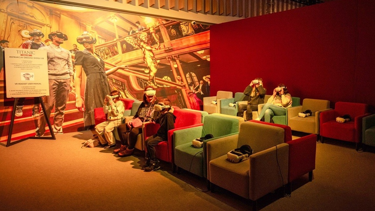 People wearing VR headsets in a Titanic-themed room with colourful chairs.