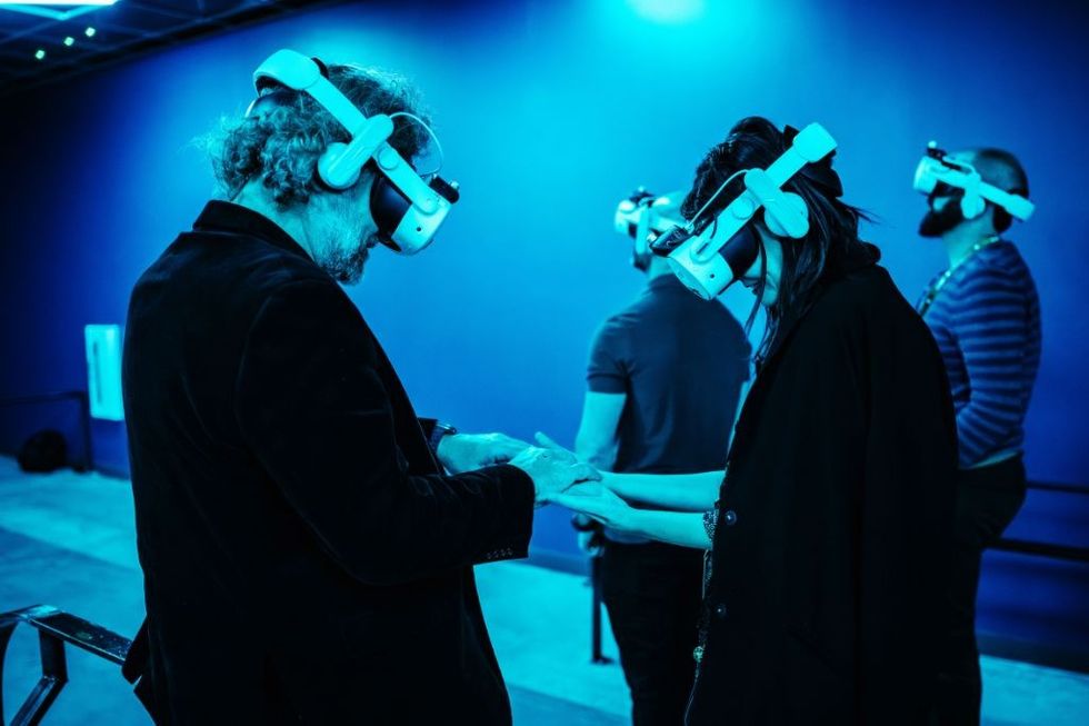 People wearing VR headsets interact in a blue-lit room.