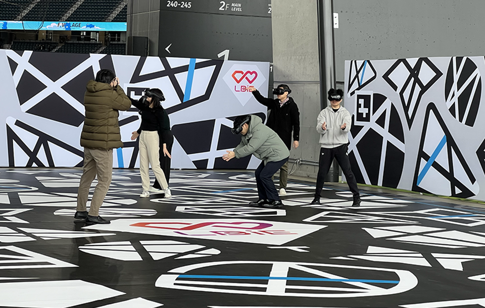 People wearing VR headsets interact in a geometric-patterned room.