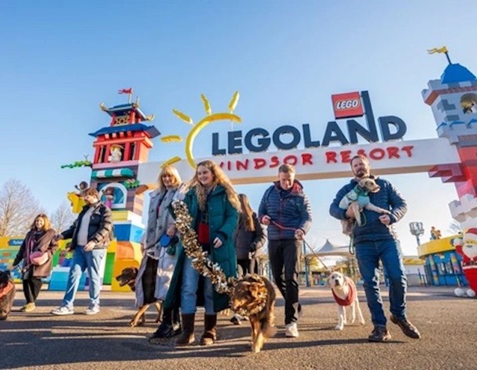 People with dogs entering LEGOLAND Windsor Resort under a sunny sky.