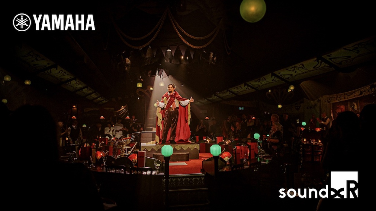 Performer in a red robe on a dimly lit stage, with Yamaha and sound graphic logos.