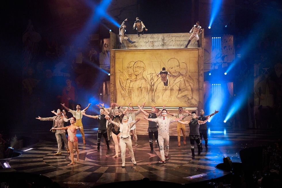 Performers in a circus show posing in front of a large illuminated backdrop, Cirque du Soleil's Joya