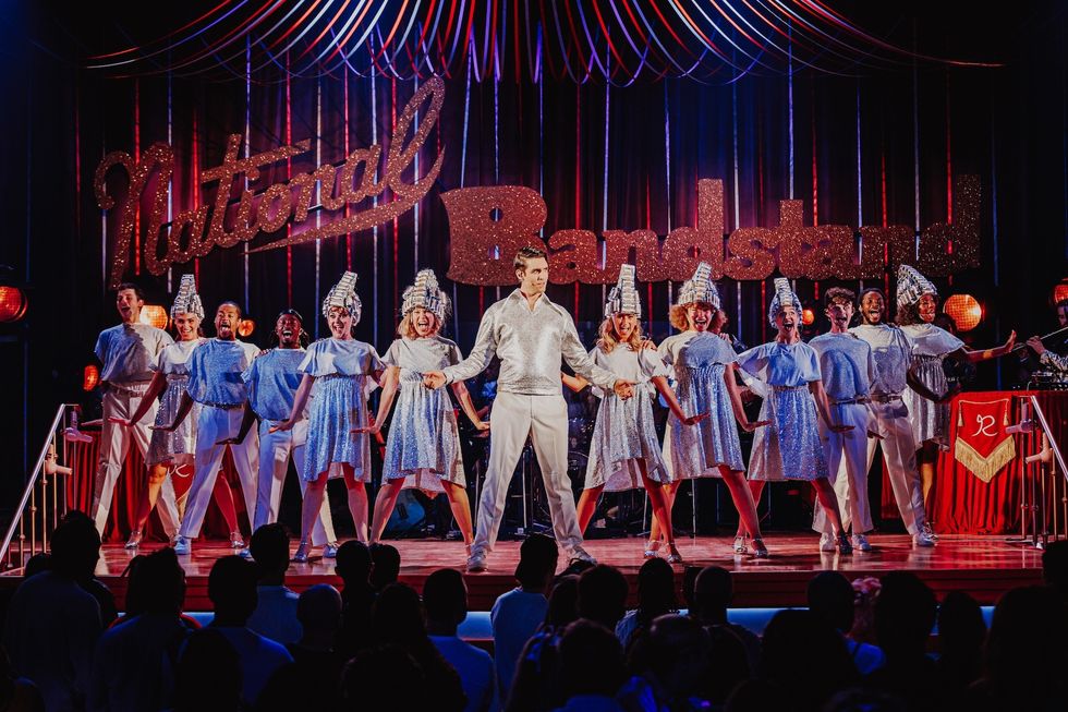 Performers in sparkly outfits on stage under "National Bandstand" sign.