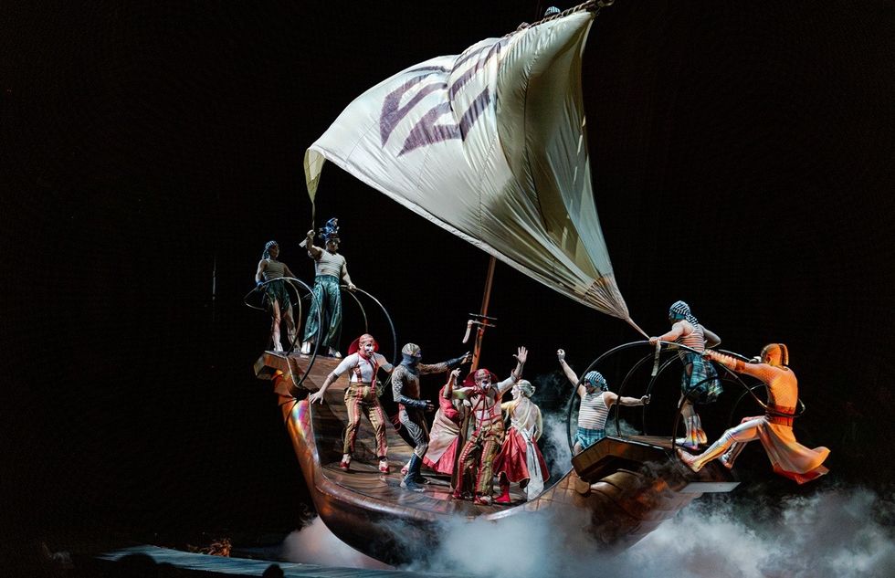 Performers on a stylized boat with a large sail in a theatrical show.