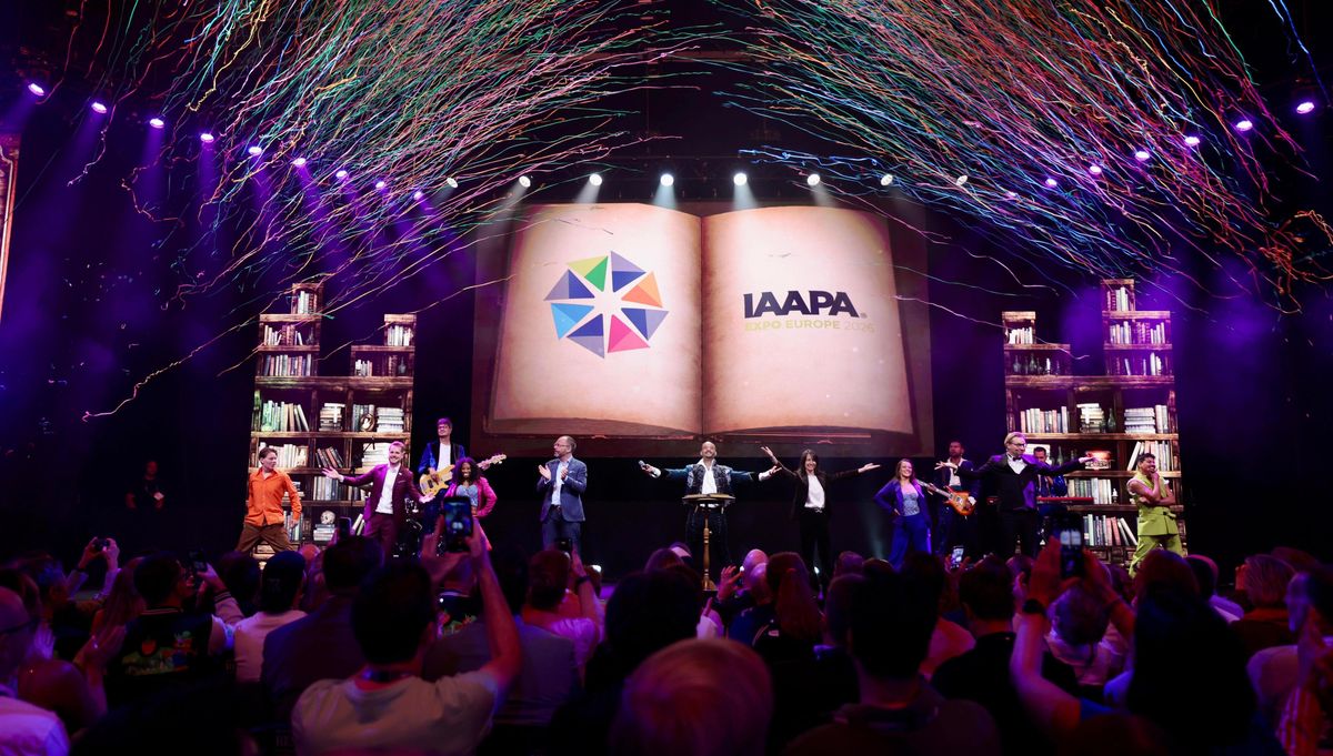 Performers on stage with confetti and a large screen displaying the IAAPA logo.