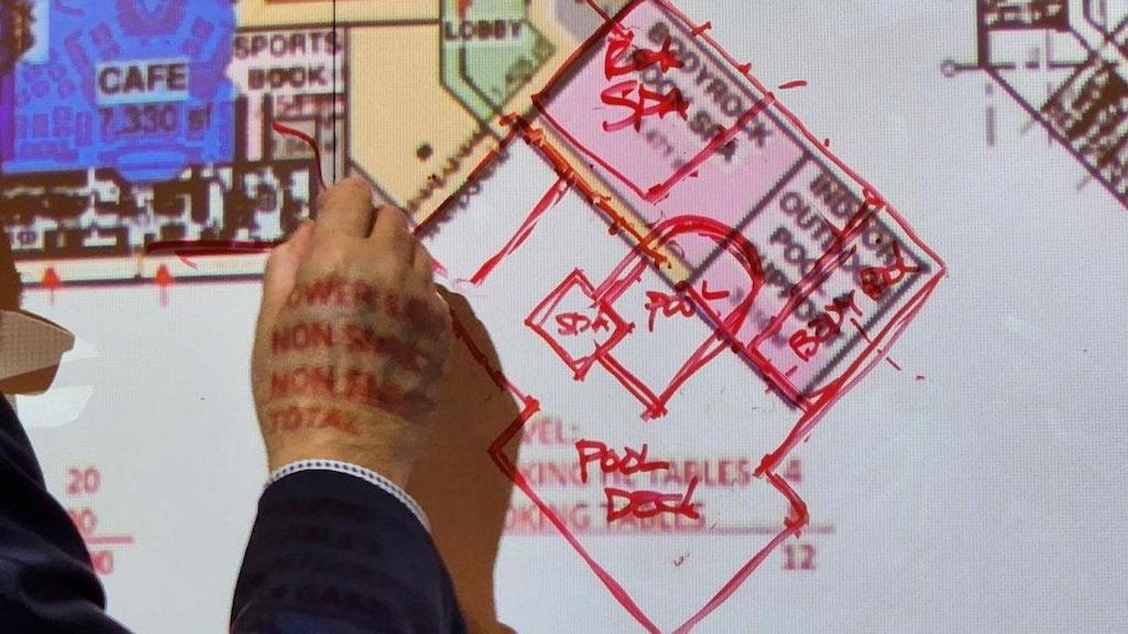 Person annotating a projected floor plan with red ink.