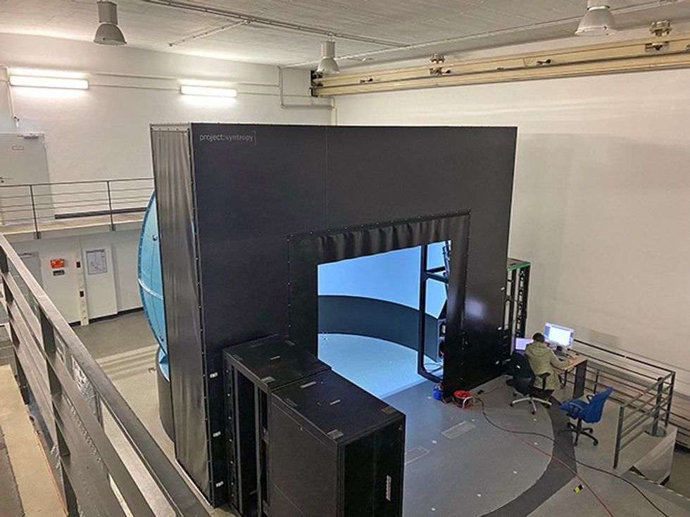 Person at a desk in a large virtual environment room with screens and equipment at the ISTAR fixed-base flight simulator