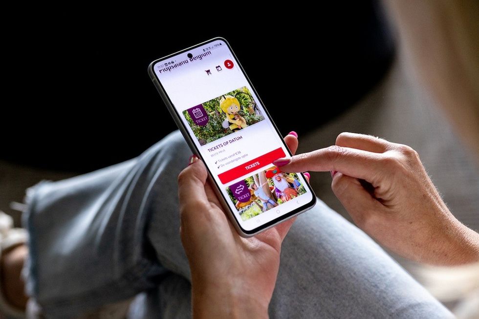 Person buying theme park tickets on a smartphone with a colorful app interface.