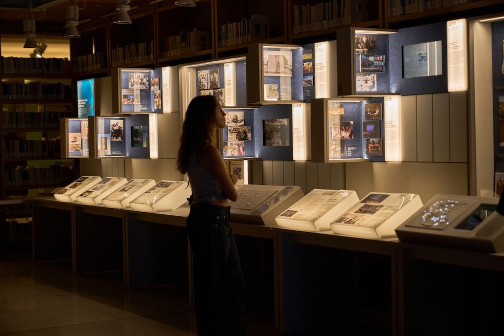 Person examining illuminated historical exhibits in a dimly-lit room.
