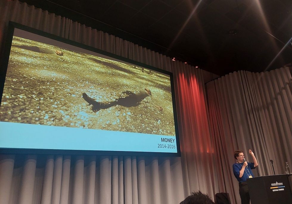 Person giving a presentation on Stapferhaus exhibition "Money" with a large screen image.