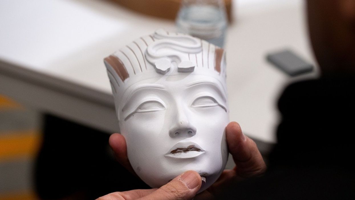 Person holding a small sculpture of an ancient Egyptian face.