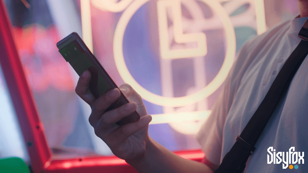 Person holding a smartphone near neon lights, wearing a strap.
