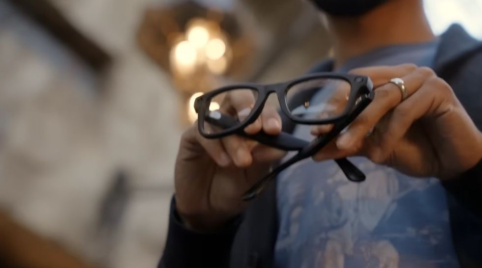 Person holding black eyeglasses, soft focus background.
