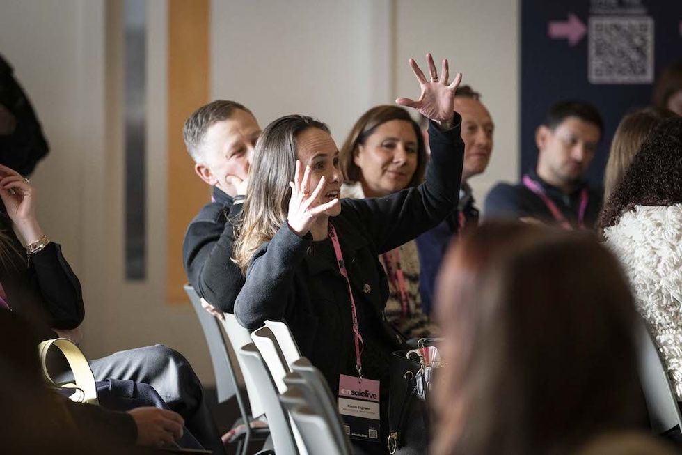 Person in an audience at On Sale Live 2026 passionately speaking, surrounded by attentive listeners.