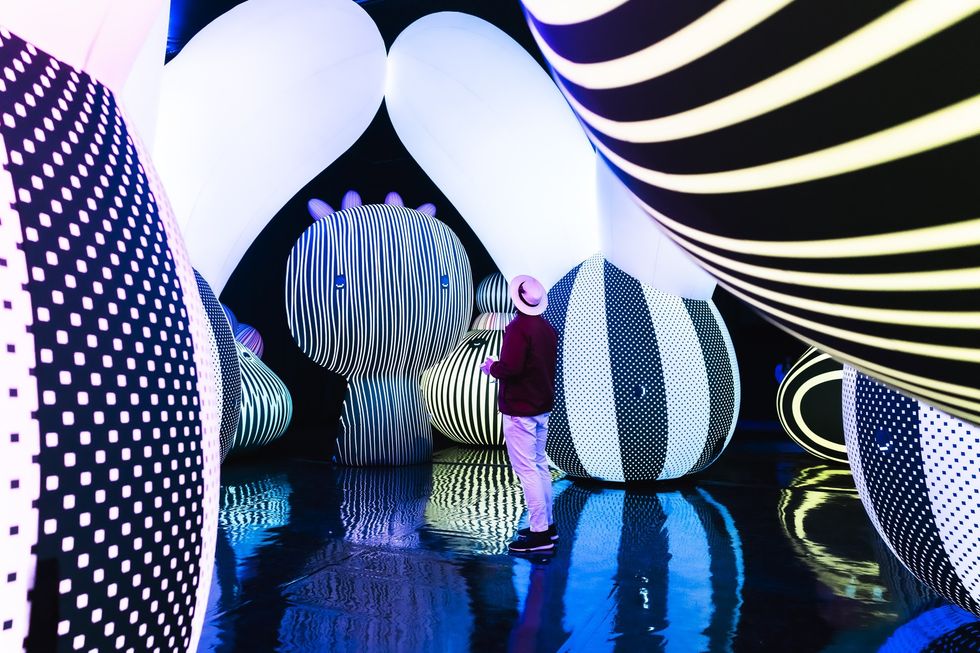 Person in colorful, striped, inflatable art installation with reflective floor.