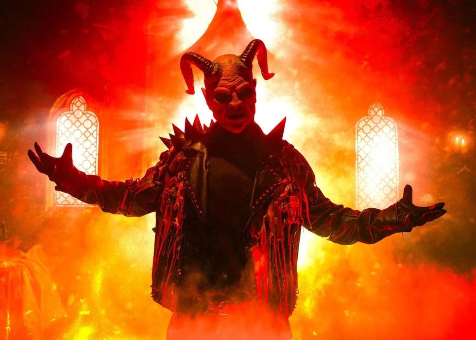 Person in devil costume with horns, in front of a fiery, red-lit background at Thorpe Park Fright Nights