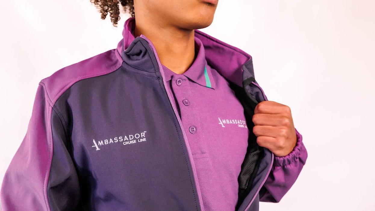 Person in purple Ambassador Cruise Line uniform, jacket partially open, white background.