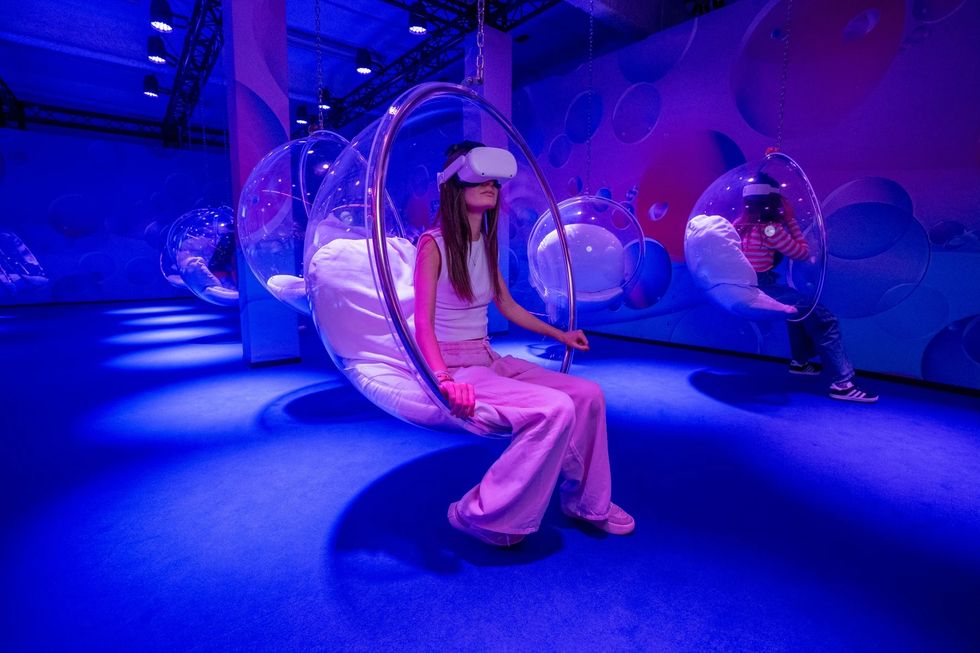 Person in VR headset sits in a spherical chair in a vibrant purple room at Bubble Planet