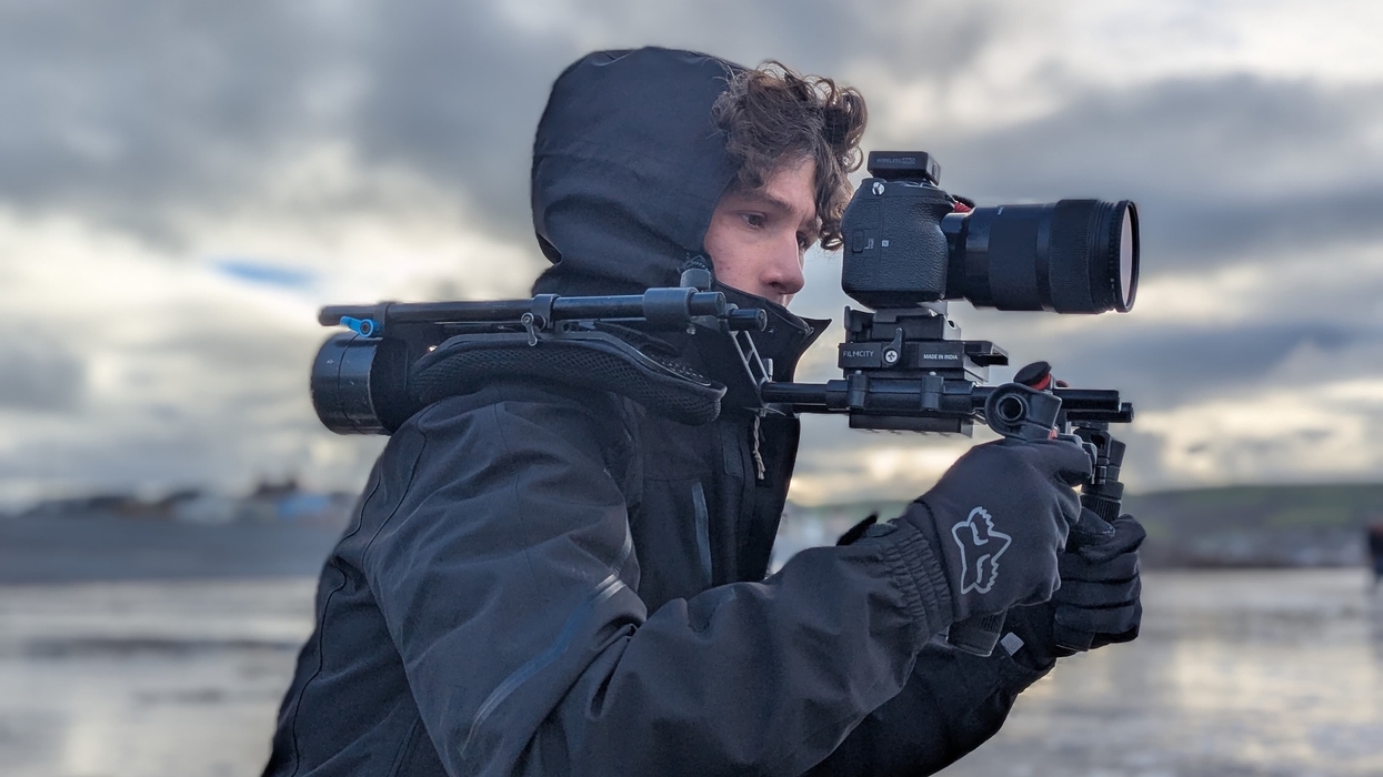 Person in winter gear filming outdoors with a camera rig.