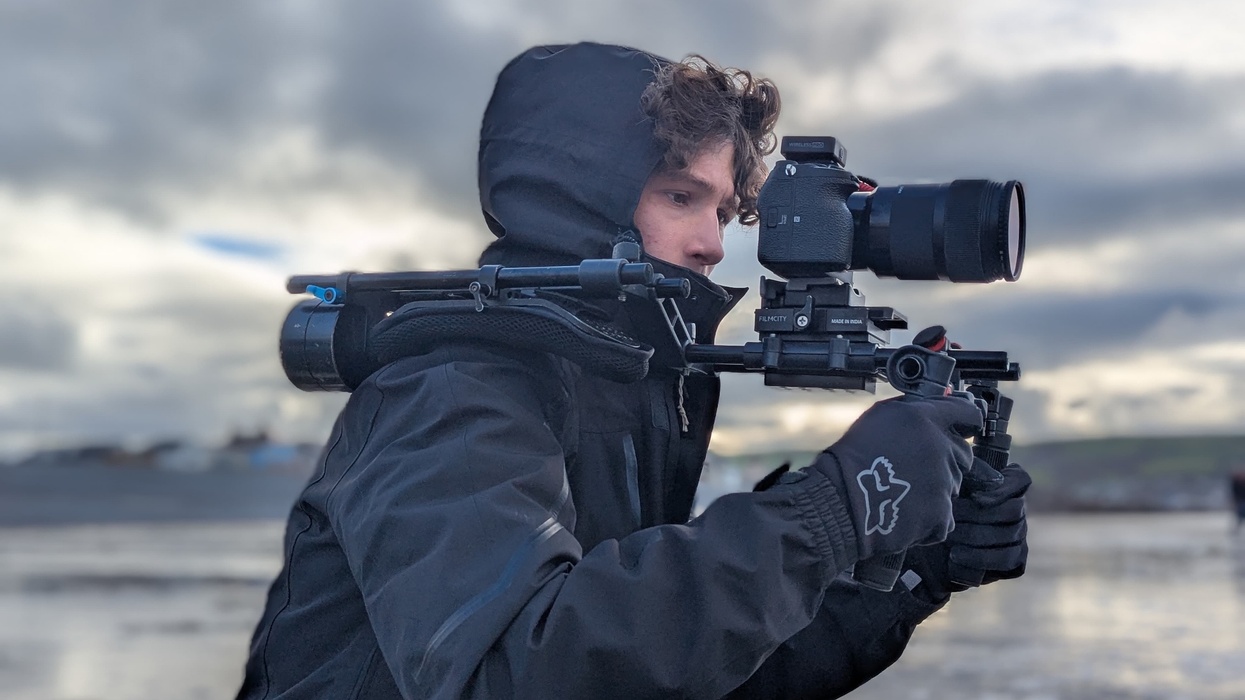 Person in winter gear filming outdoors with a camera rig.