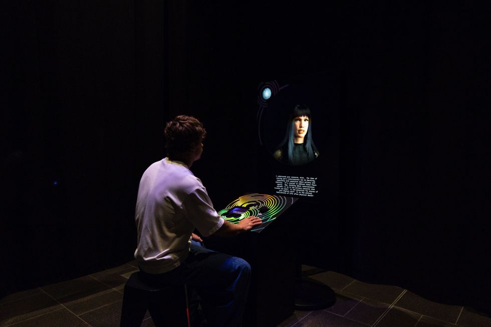 Person interacting with a colorful digital display in a dark room.