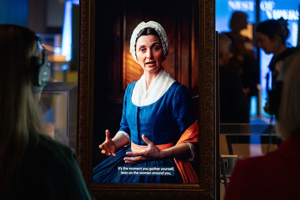 Person interacting with a historical portrait in a museum exhibit.