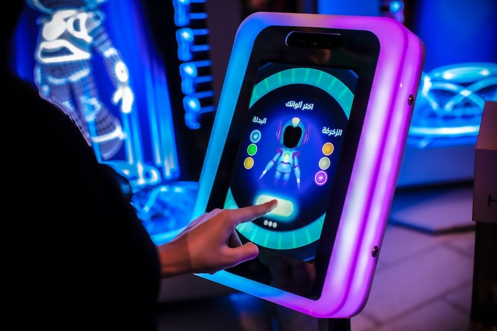 Person interacting with a neon-lit touchscreen display in a futuristic setting, Become a Guardian of Al Wasl