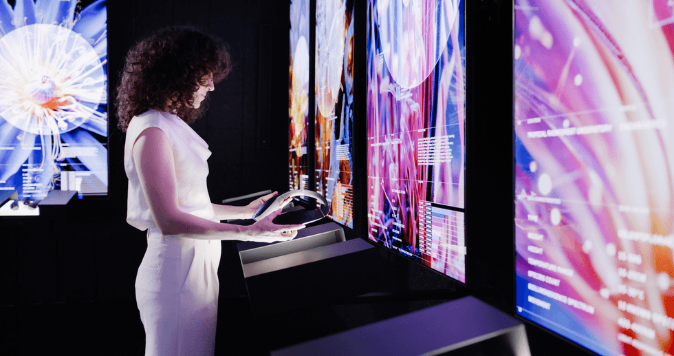 Person interacting with colorful digital screens in a dimly lit, modern exhibition at Dataland