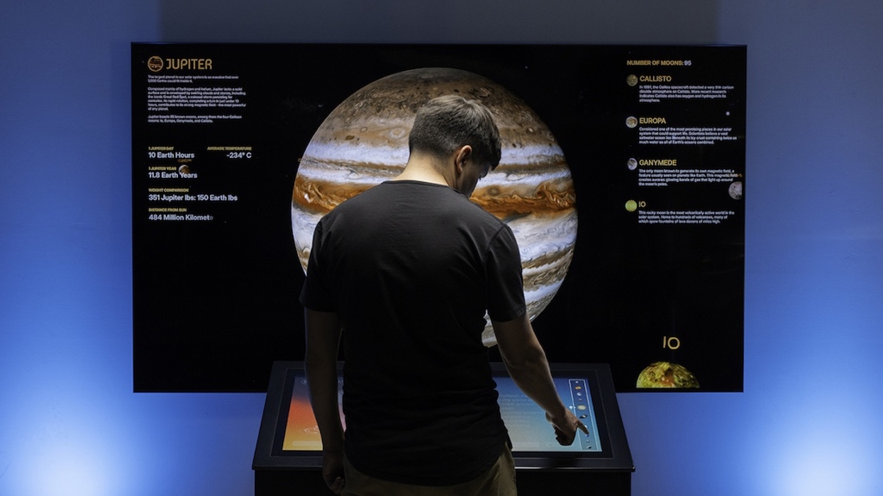 Person interacts with a digital display about Jupiter in an exhibit.
