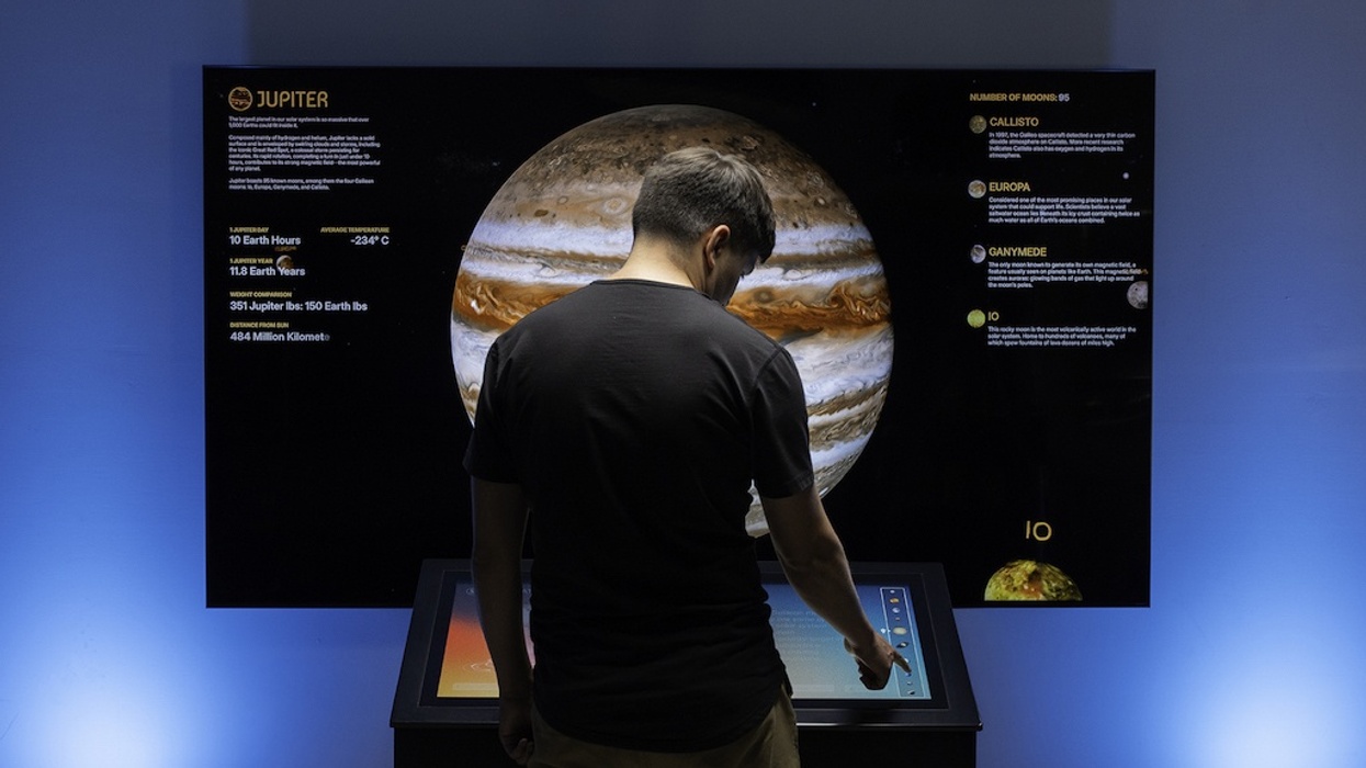 Person interacts with a digital display about Jupiter in an exhibit.