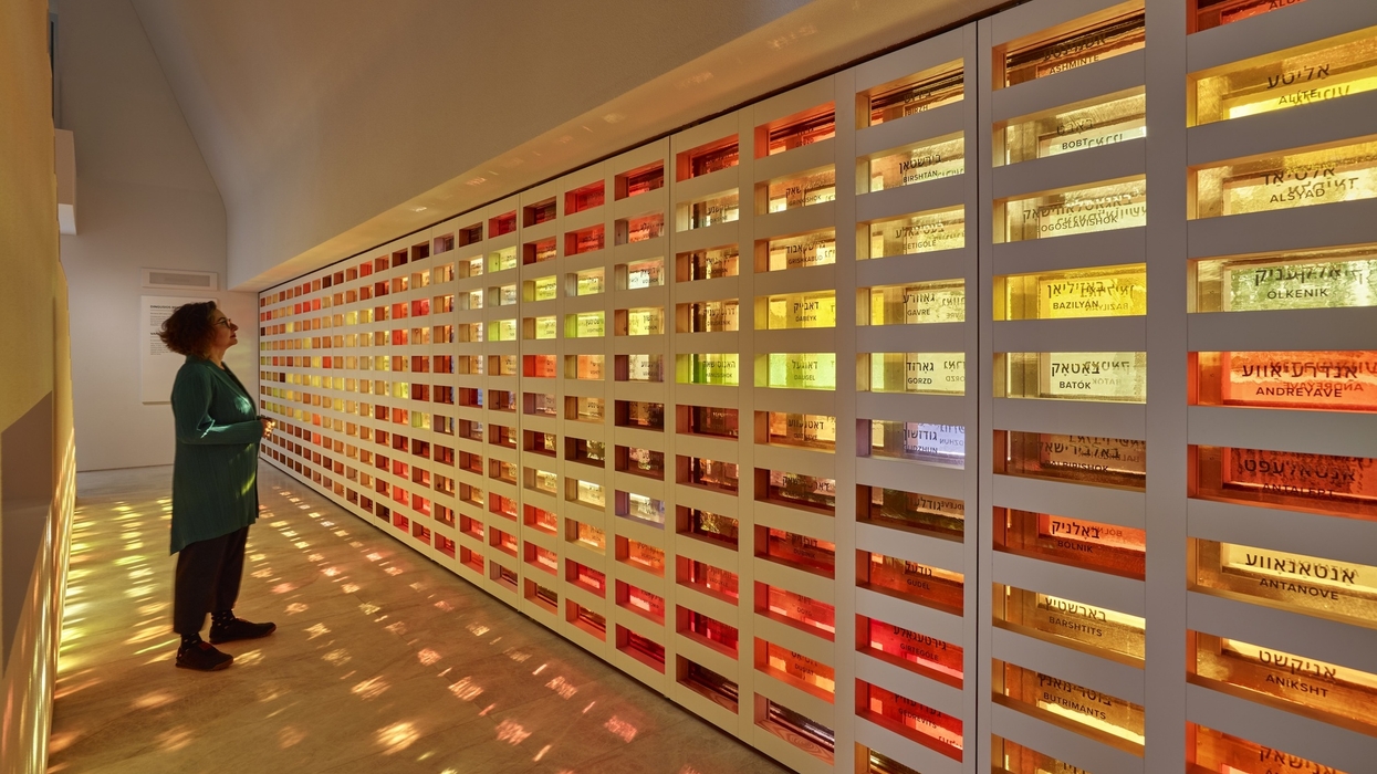 Person observing a colorful, illuminated wall installation with names.