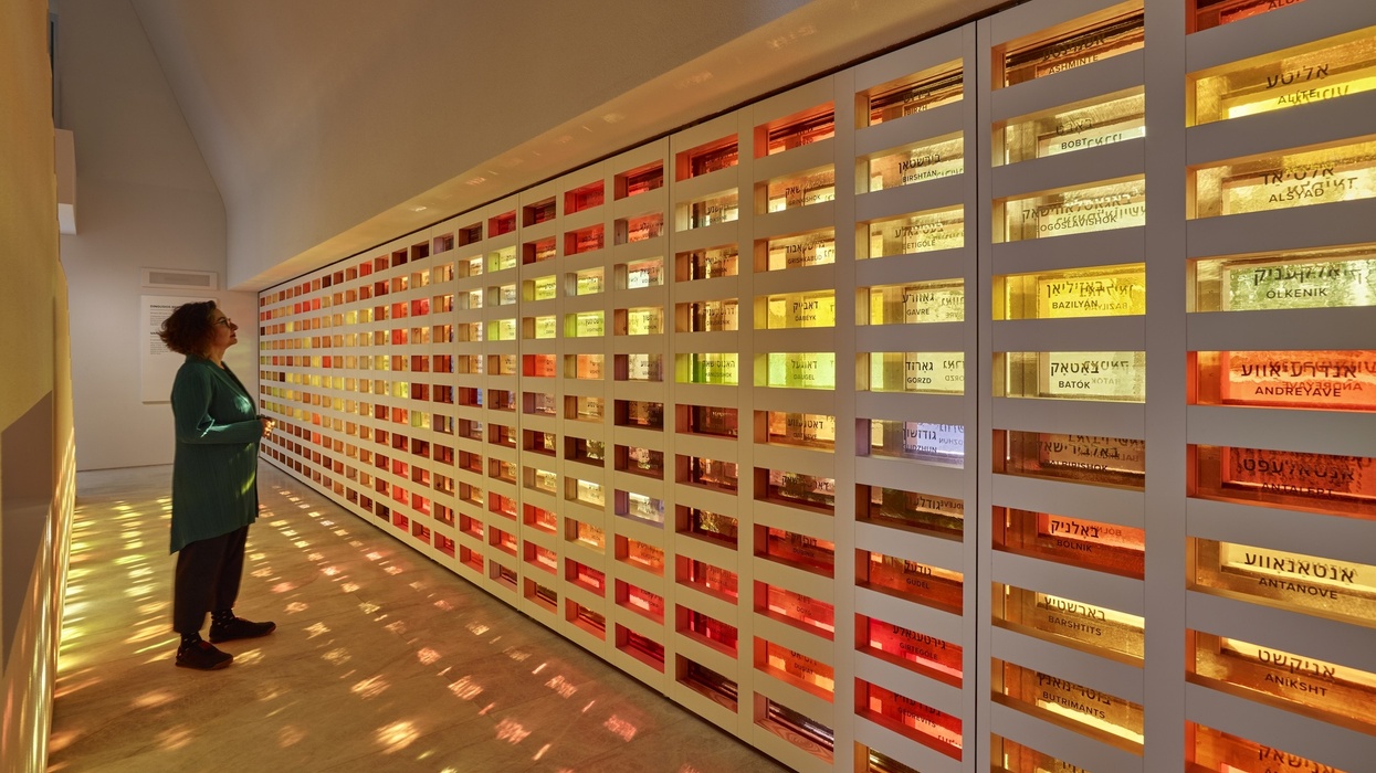 Person observing a colorful, illuminated wall installation with names.
