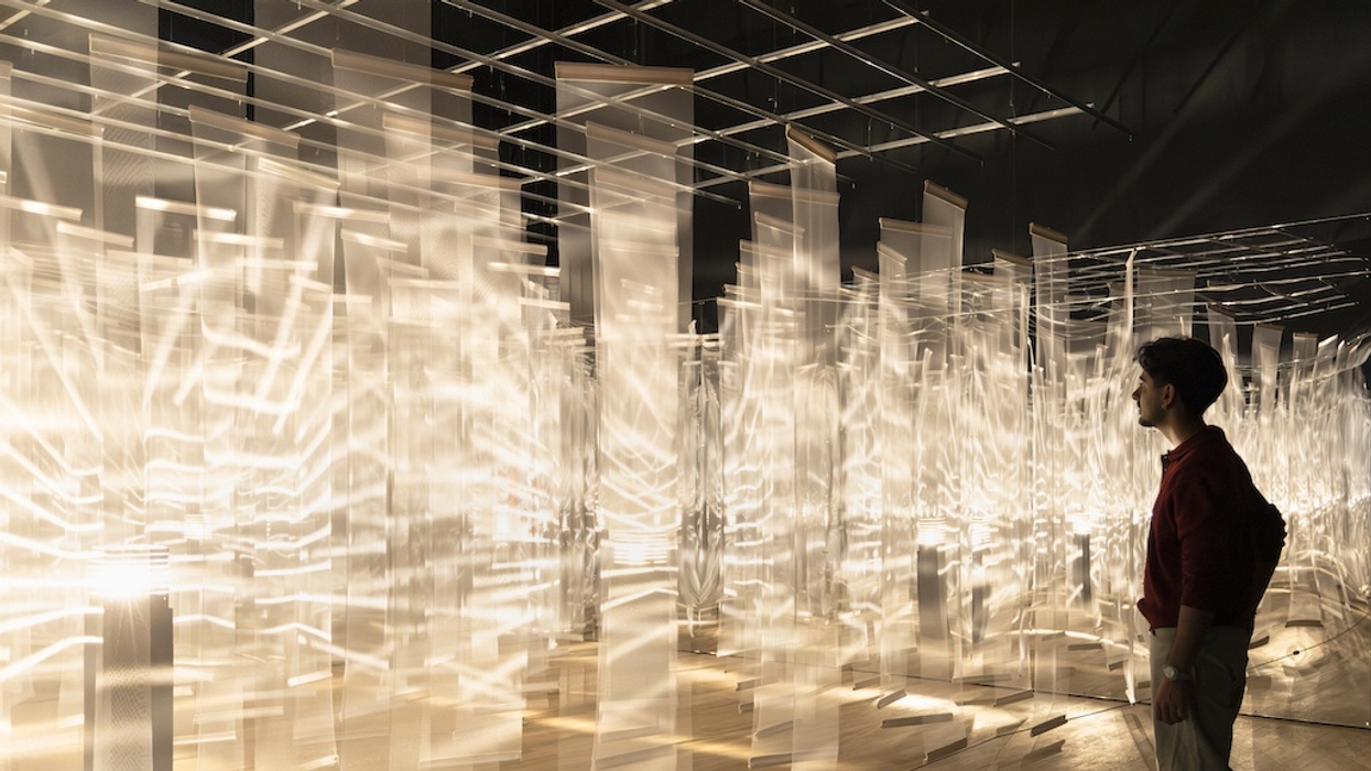 Person observing illuminated translucent panels in a dark room, Julio Le Parc exhibition Tate Modern