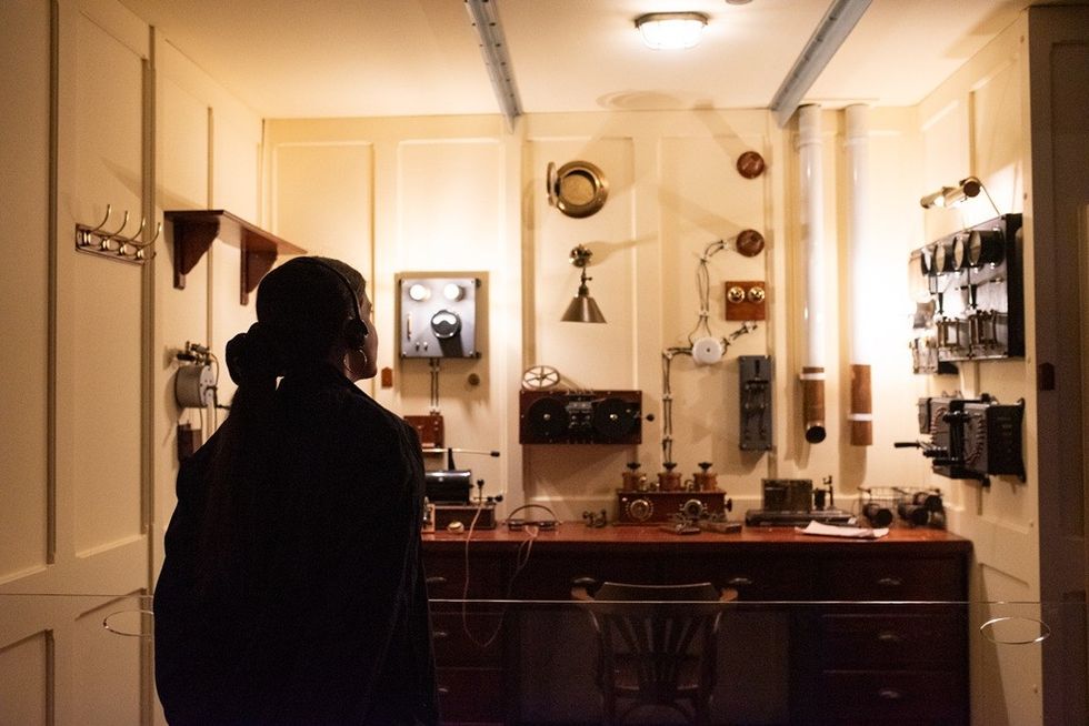 Person observing vintage radio equipment in a dimly lit room.